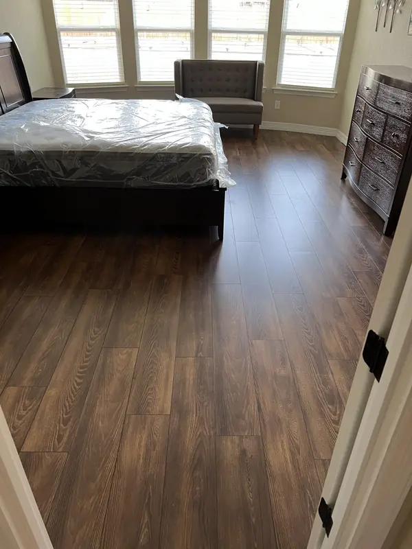 Dark hardwood flooring installed in a furnished bedroom