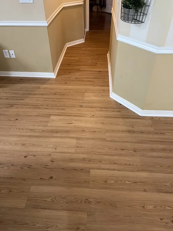 Hardwood flooring meeting white baseboard in a finished hallway