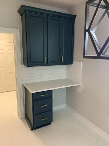 Navy blue built in desk and upper cabinets with white subway tile