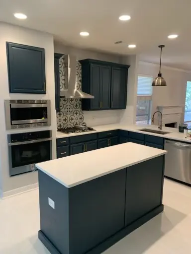 Remodeled kitchen with navy cabinets, white quartz island and pendant lighting