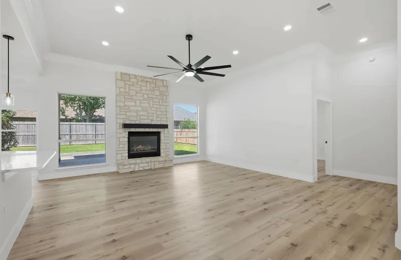 Living room with a stone fireplace between two windows onto the back garden