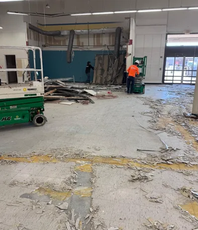 Crew taking down an interior wall from a scissor lift during a retail strip out