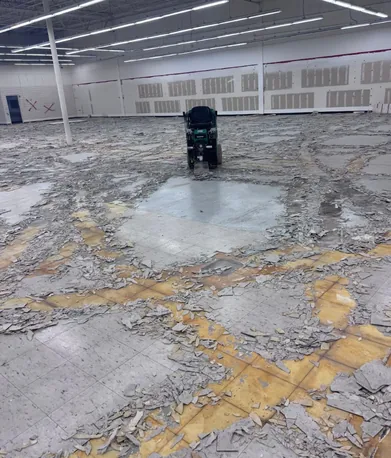 Ride on tile scraper working across a retail floor during strip out